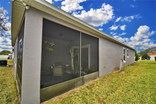 view of side of home with a yard, a sunroom, and central air condition unit