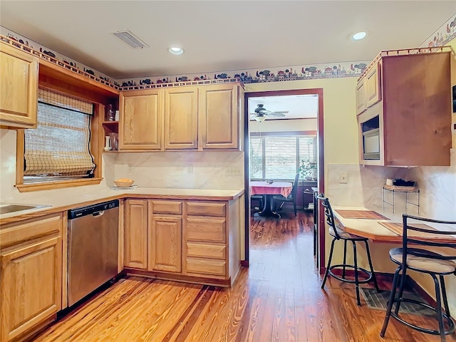 kitchen with stainless steel dishwasher, backsplash, and light hardwood / wood-style flooring