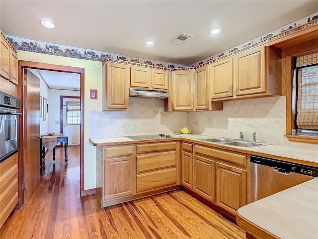 kitchen featuring light brown cabinetry, decorative backsplash, light wood-type flooring, and appliances with stainless steel finishes