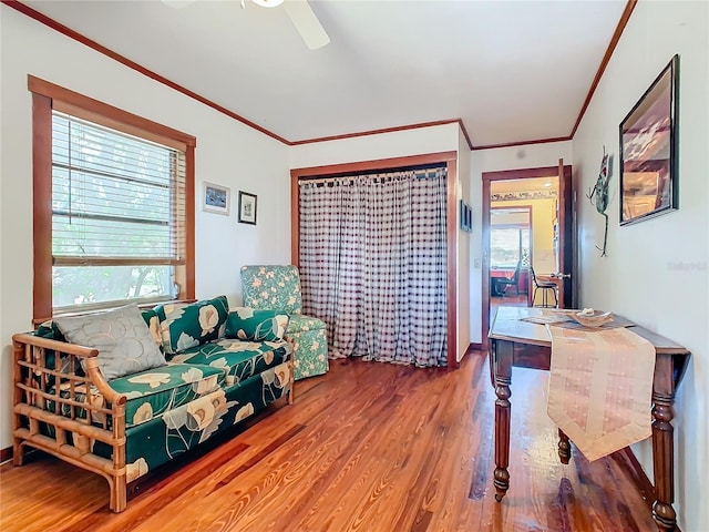 interior space with crown molding, wood-type flooring, a wealth of natural light, and ceiling fan