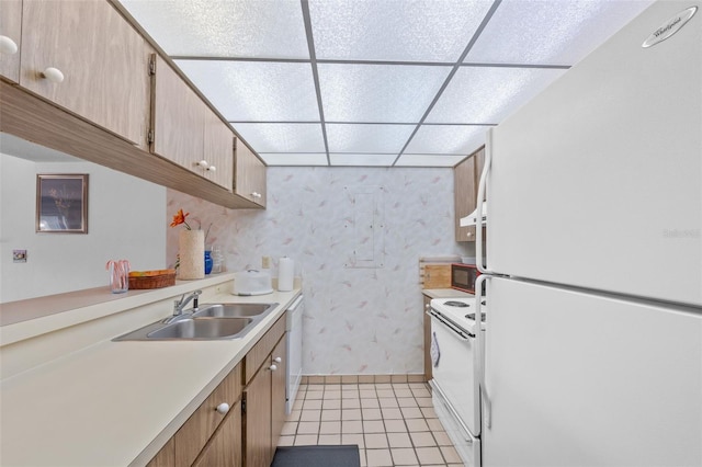 kitchen featuring white appliances, light tile patterned floors, sink, and a drop ceiling