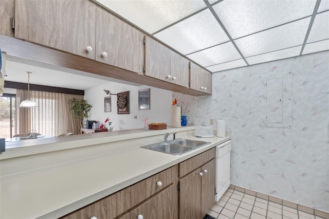 kitchen with light tile patterned flooring, sink, a paneled ceiling, decorative light fixtures, and white dishwasher