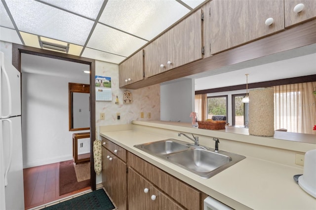 kitchen featuring sink, hanging light fixtures, hardwood / wood-style flooring, white fridge, and a drop ceiling