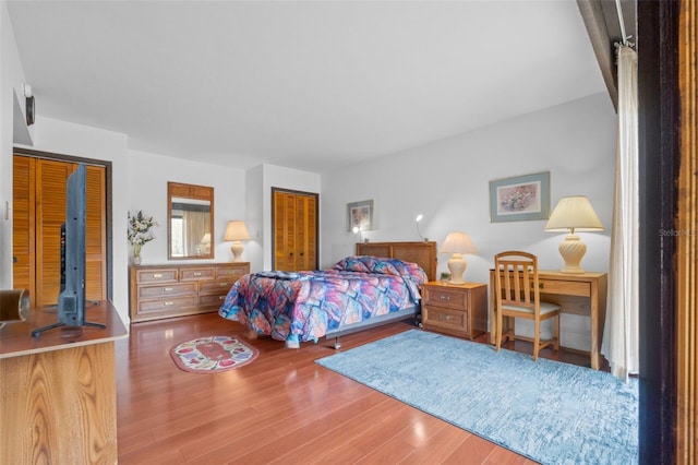 bedroom with hardwood / wood-style flooring and multiple closets