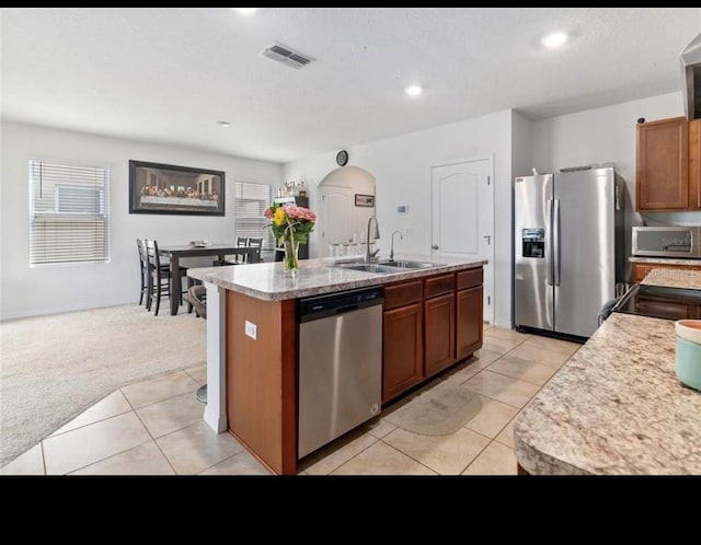 kitchen with sink, appliances with stainless steel finishes, plenty of natural light, an island with sink, and light colored carpet