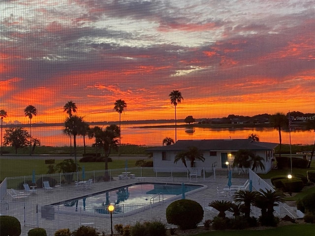 pool at dusk with a water view and a patio