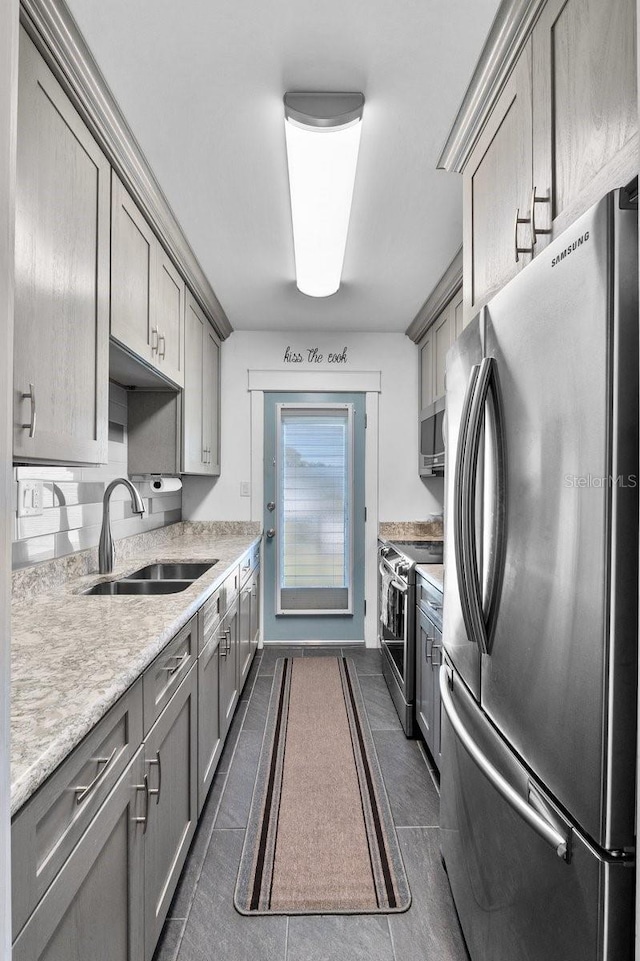 kitchen with sink, gray cabinets, dark tile patterned floors, stainless steel appliances, and light stone countertops