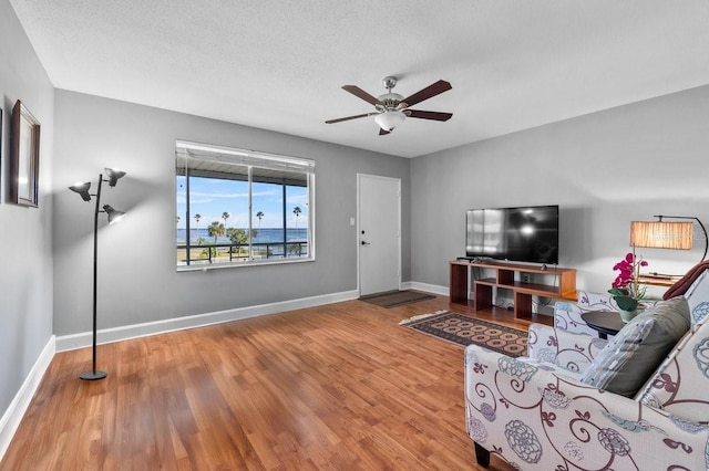 living room with ceiling fan, wood-type flooring, and a textured ceiling