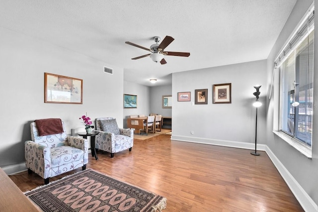 sitting room featuring ceiling fan, hardwood / wood-style floors, and a textured ceiling