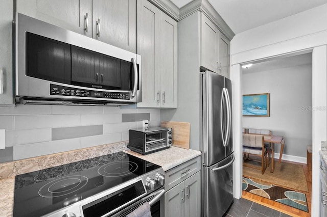 kitchen with stainless steel appliances, dark tile patterned floors, gray cabinets, and backsplash