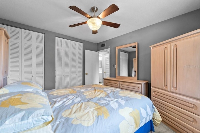 bedroom with ceiling fan and multiple closets