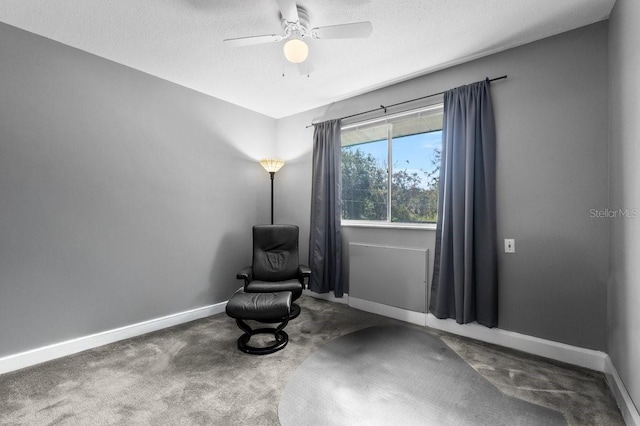 living area featuring carpet flooring, a textured ceiling, and ceiling fan