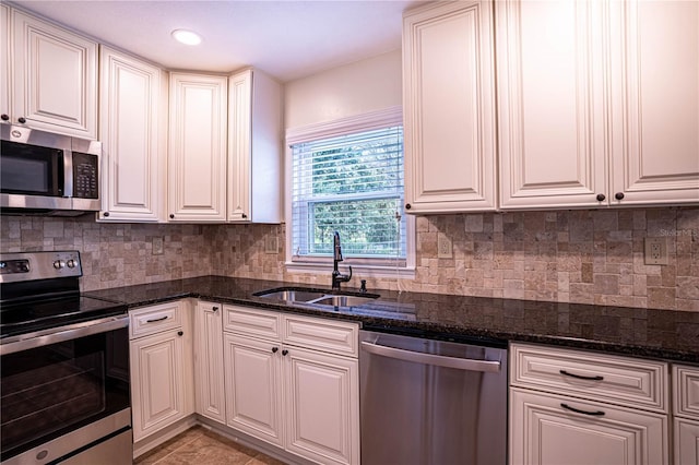 kitchen with appliances with stainless steel finishes, sink, white cabinets, and dark stone counters