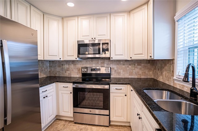 kitchen featuring white cabinetry, appliances with stainless steel finishes, sink, and dark stone countertops