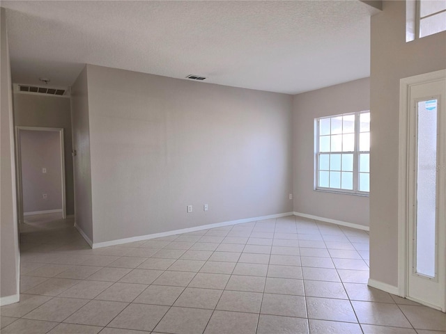 spare room featuring light tile patterned floors and a textured ceiling