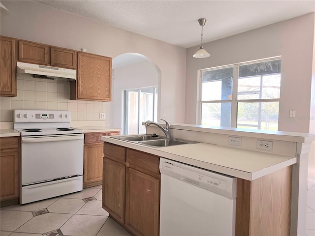 kitchen featuring pendant lighting, sink, decorative backsplash, light tile patterned floors, and white appliances