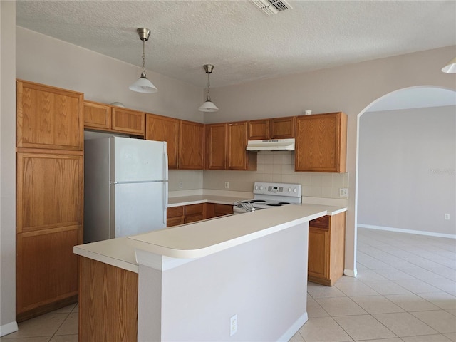 kitchen with light tile patterned floors, white appliances, backsplash, a kitchen island, and decorative light fixtures