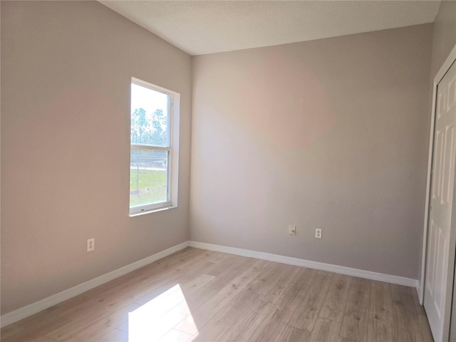 unfurnished room featuring light hardwood / wood-style flooring and a textured ceiling