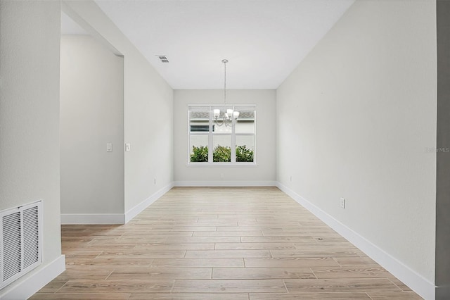 unfurnished dining area with an inviting chandelier and light hardwood / wood-style flooring