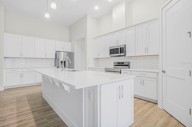 kitchen with white cabinetry, appliances with stainless steel finishes, and a kitchen island with sink