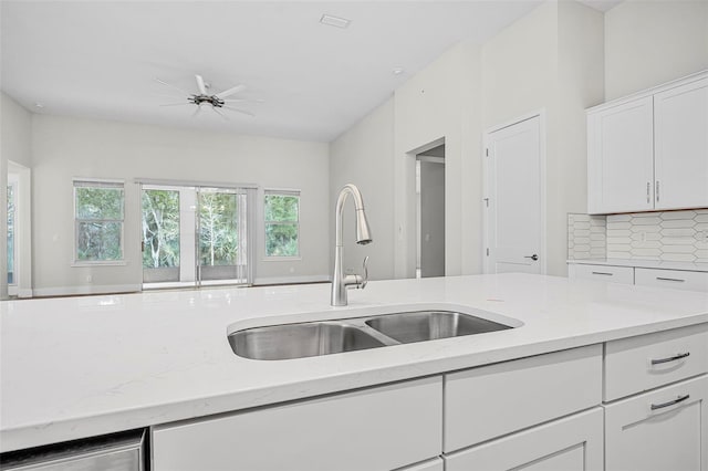 kitchen with white cabinetry, sink, backsplash, and light stone countertops