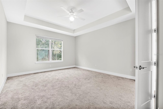 carpeted empty room featuring a tray ceiling and ceiling fan