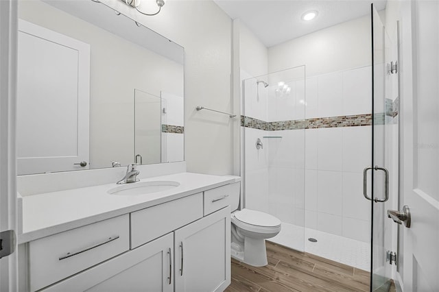 bathroom featuring vanity, toilet, an enclosed shower, and wood-type flooring