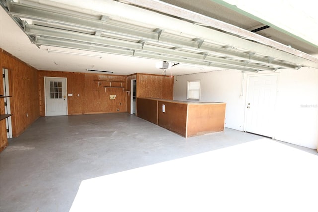 garage featuring a garage door opener and wooden walls