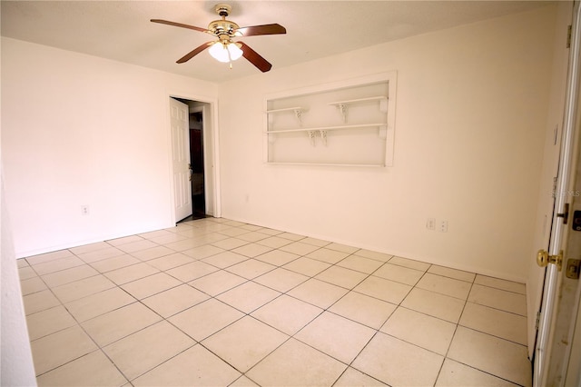 tiled spare room featuring built in shelves and ceiling fan