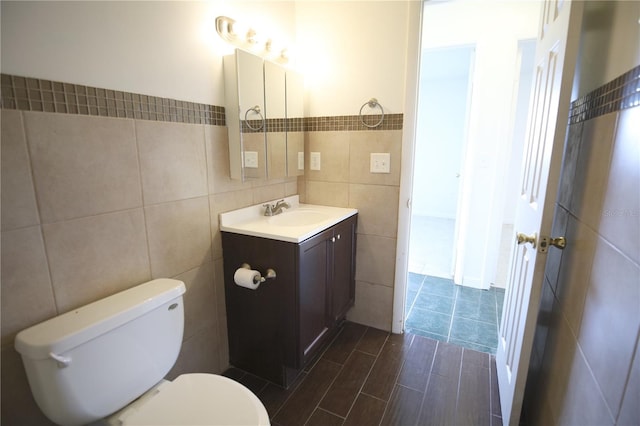 bathroom featuring vanity, toilet, hardwood / wood-style floors, and tile walls