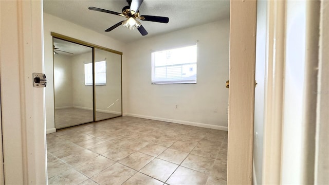 unfurnished bedroom featuring ceiling fan, a closet, and light tile patterned floors