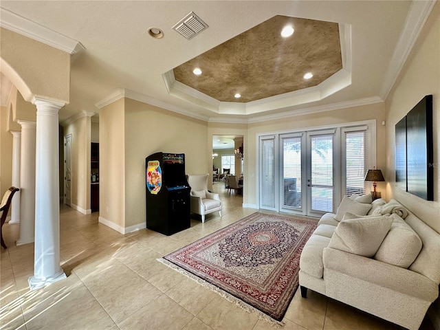 tiled living room featuring a tray ceiling, ornamental molding, decorative columns, and french doors