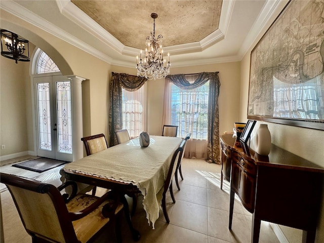 tiled dining space featuring an inviting chandelier, a healthy amount of sunlight, a tray ceiling, and ornate columns