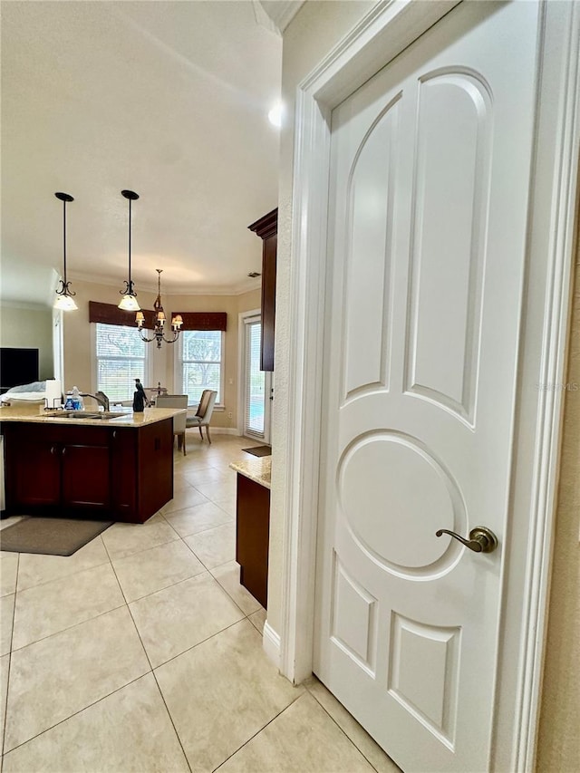 kitchen with light tile patterned flooring, crown molding, an inviting chandelier, a kitchen island, and pendant lighting