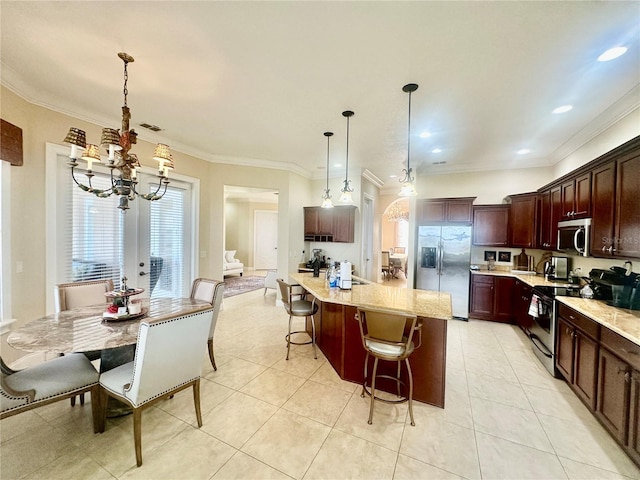 kitchen with appliances with stainless steel finishes, decorative light fixtures, a breakfast bar area, a kitchen island with sink, and light stone counters