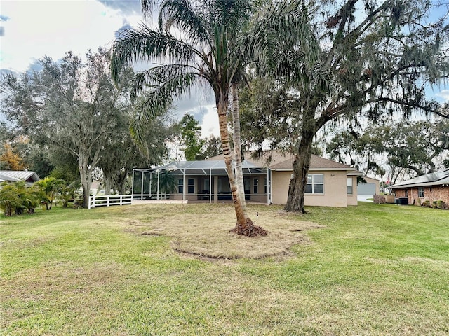 back of property with glass enclosure and a lawn