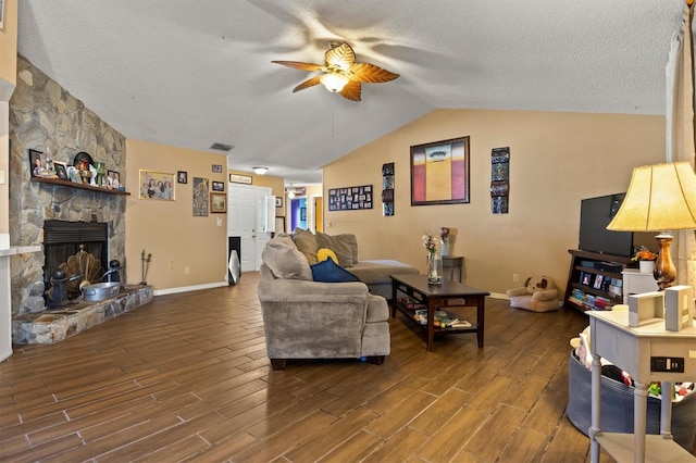 living room featuring lofted ceiling, a stone fireplace, a textured ceiling, dark hardwood / wood-style flooring, and ceiling fan