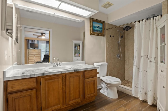 bathroom with walk in shower, toilet, a skylight, vanity, and ceiling fan