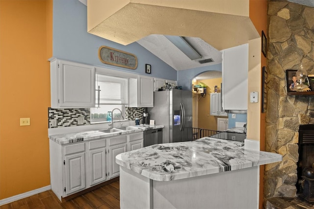 kitchen with tasteful backsplash, sink, white cabinets, kitchen peninsula, and stainless steel appliances