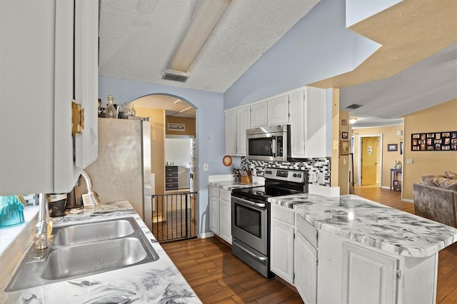 kitchen with lofted ceiling, sink, dark wood-type flooring, white cabinetry, and stainless steel appliances