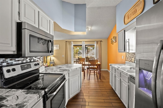 kitchen with backsplash, stainless steel appliances, and white cabinets