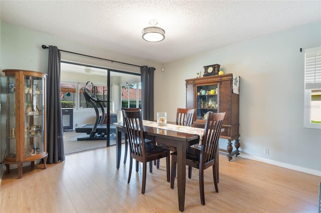 dining space featuring light hardwood / wood-style floors and a textured ceiling