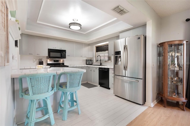 kitchen featuring white cabinetry, a raised ceiling, sink, and black appliances