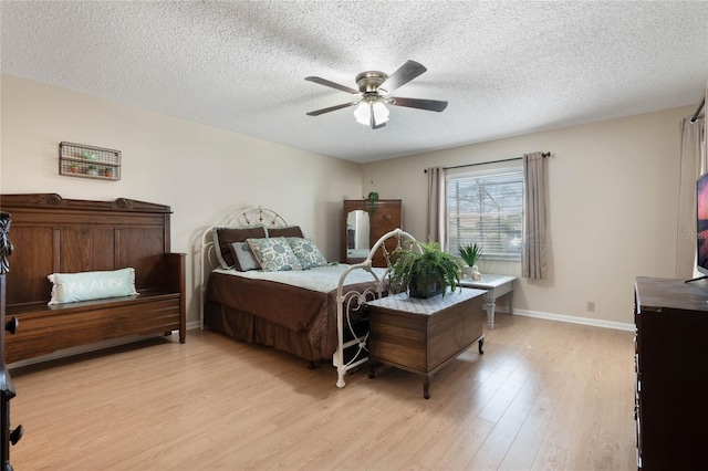 bedroom with ceiling fan, light hardwood / wood-style floors, and a textured ceiling