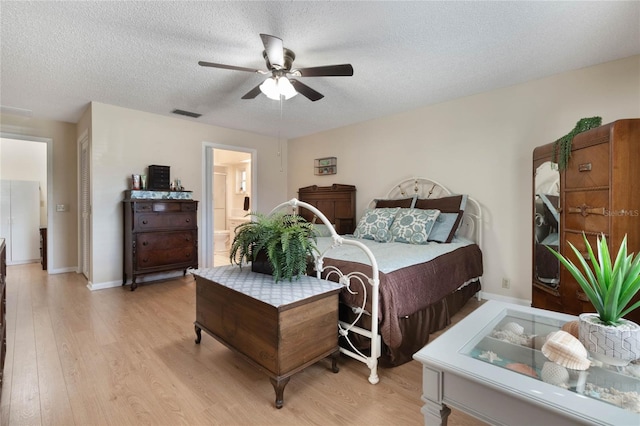 bedroom featuring connected bathroom, light hardwood / wood-style flooring, a textured ceiling, and ceiling fan