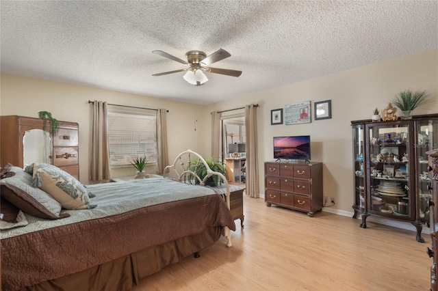 bedroom featuring ceiling fan, a textured ceiling, and light wood-type flooring