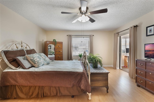 bedroom with ceiling fan, light hardwood / wood-style floors, multiple windows, and a textured ceiling