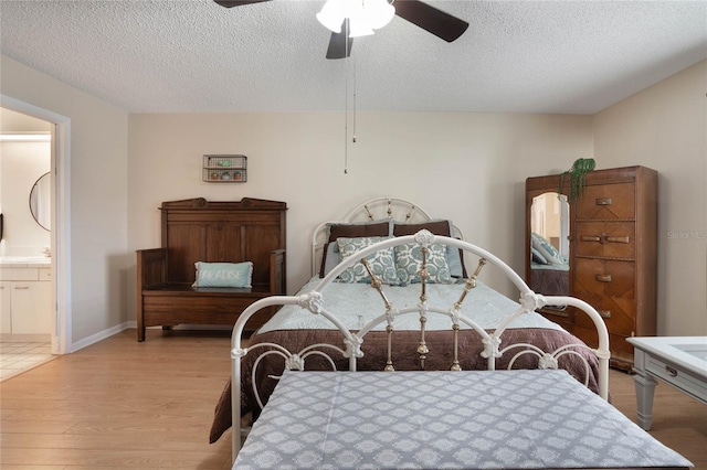 bedroom featuring ceiling fan, ensuite bathroom, a textured ceiling, and light wood-type flooring