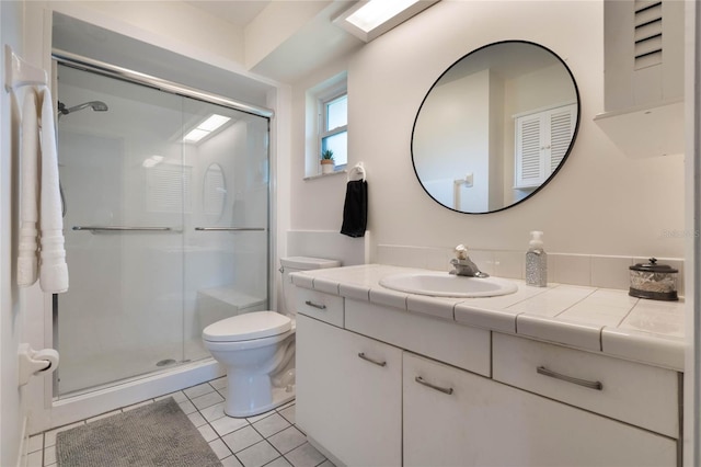 bathroom featuring vanity, toilet, tile patterned flooring, and a shower with door