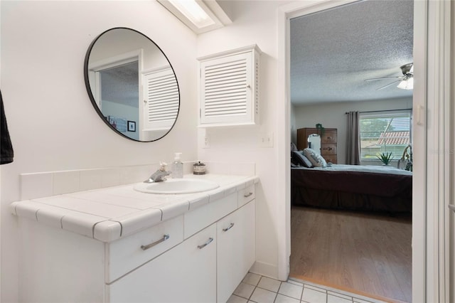 bathroom featuring tile patterned floors, ceiling fan, vanity, and a textured ceiling